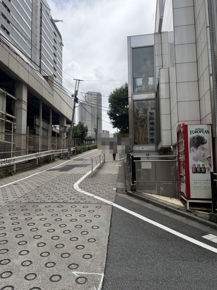 右手に自動販売機、左手に駐車場の建物
